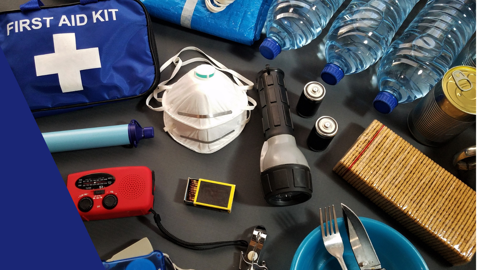 Water bottles, flash light, snacks, masks, matches, and other emergency supplies sitting on a table