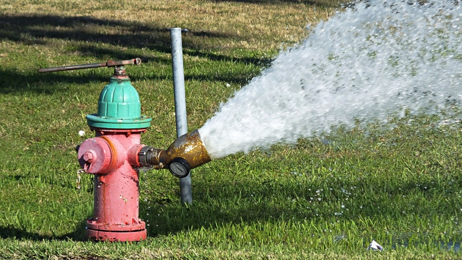 A red fire hydrant with water spraying out of the right side