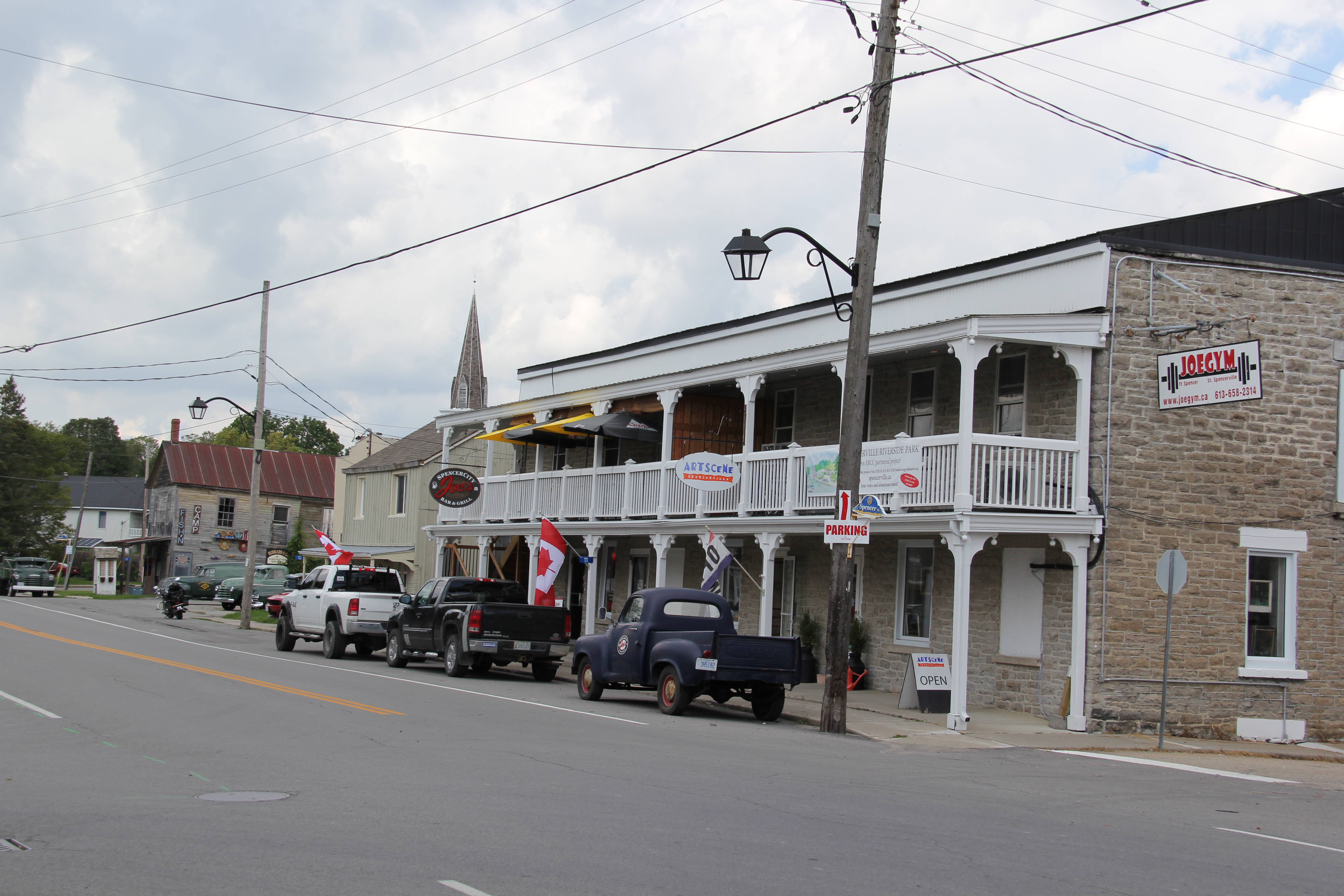 Large stone building with storefronts and cars along the road outside