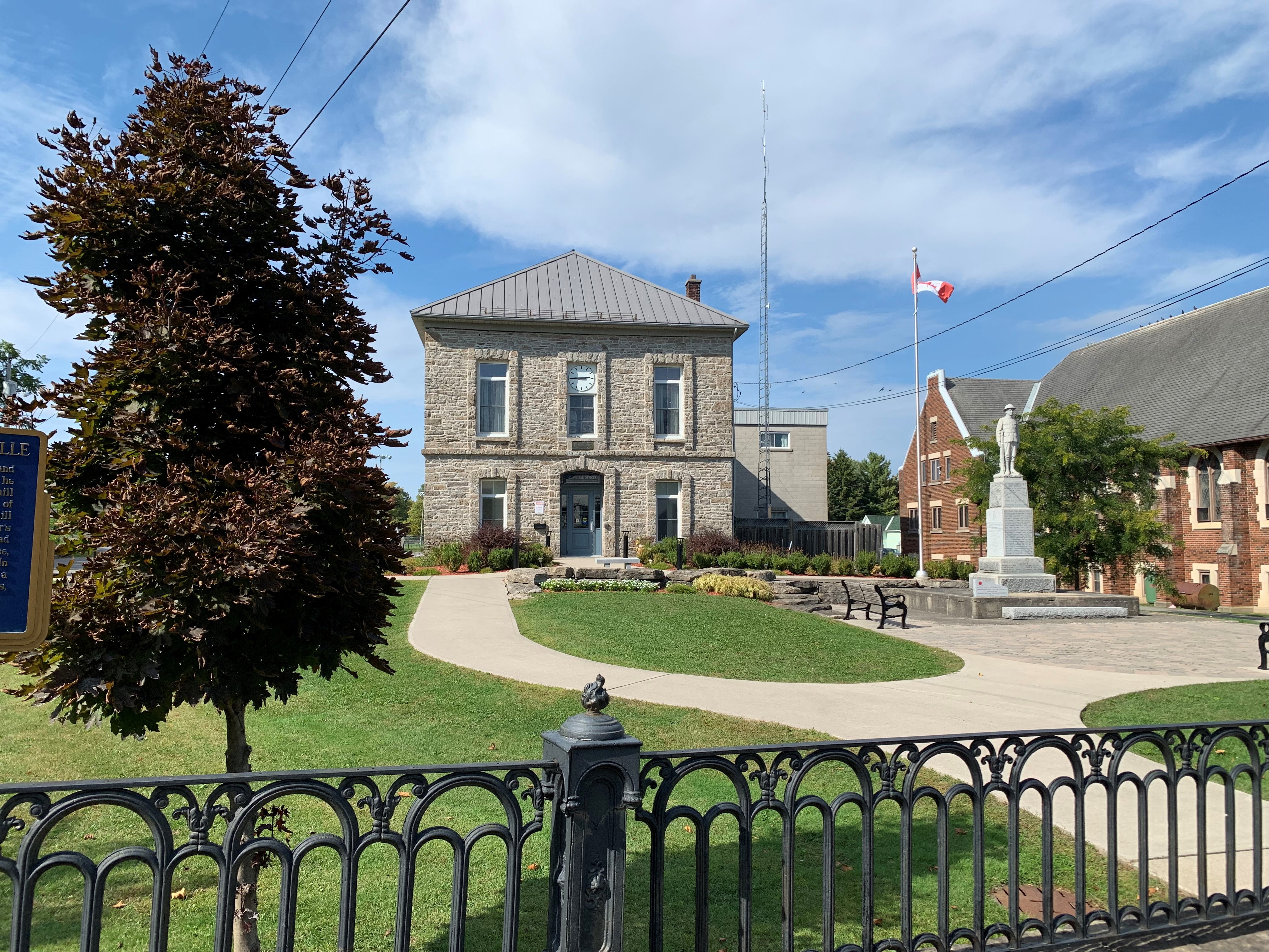 Old stone building with gardens, statue, and trees outside in the summer