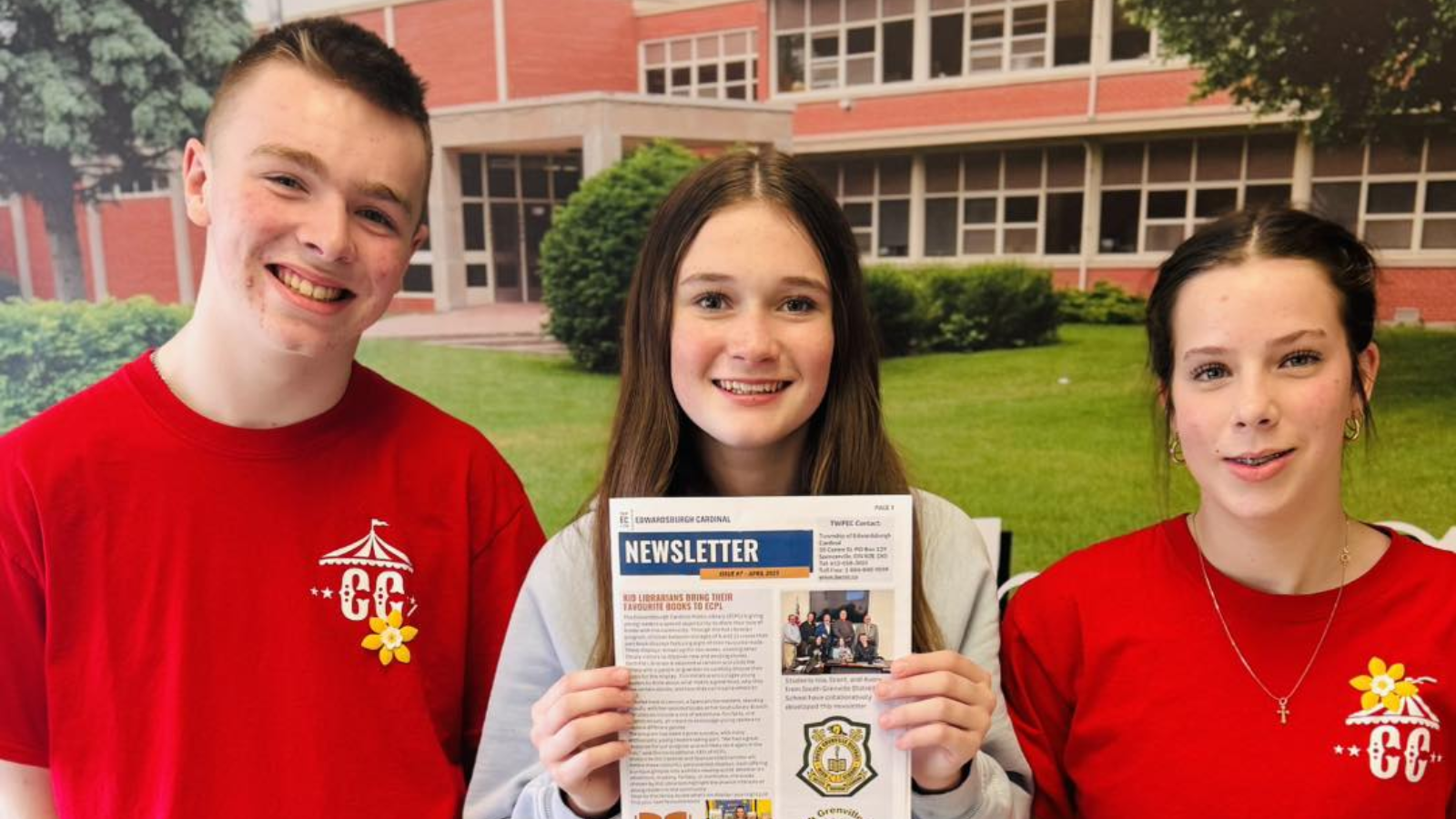 three students holding newsletter