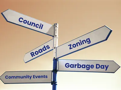 Directional signpost with arrows labeled Council, Roads, Zoning, Garbage Day, and Community Events.