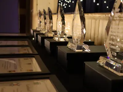 Row of framed certificates and glass awards arranged on a table.