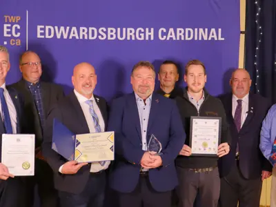 Group of people holding certificates and an award in front of TWPEC backdrop.