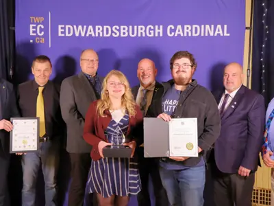 Group of people standing with certificates and an award in front of TWPEC backdrop.