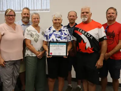Sheila Bush holding a framed award, standing with family members.