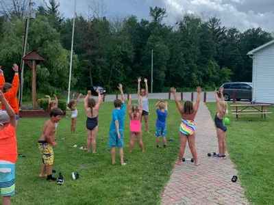 Children in swimsuits playing outside under a cloudy summer sky.