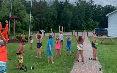 Children in swimsuits playing outside under a cloudy summer sky.
