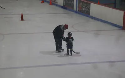 a hockey coach helping a young skater