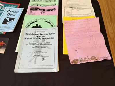 Table with skating newsletters and handwritten notes from club members.
