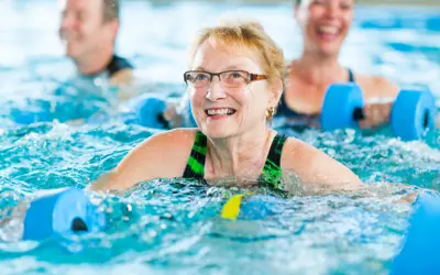 Older adults exercising in a pool with foam water weights.