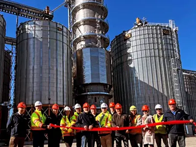 dignitaries and staff in front of new grain dryer holding red ribbon