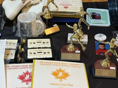 Table with figure skating trophies, skates and compulsory dance books.