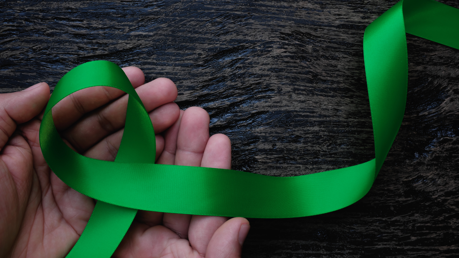 Hands holding symbolic green ribbon for organ and tissue donor awareness