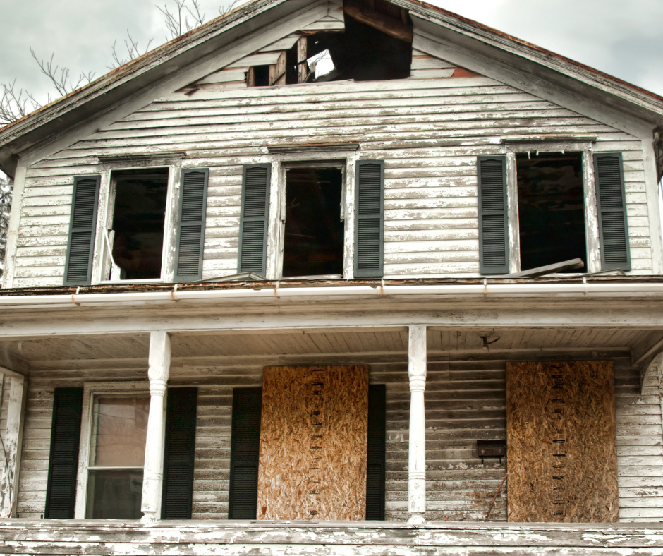 A vacant and abandoned building with boards over windows
