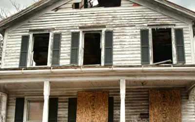 A vacant and abandoned building with boards over windows