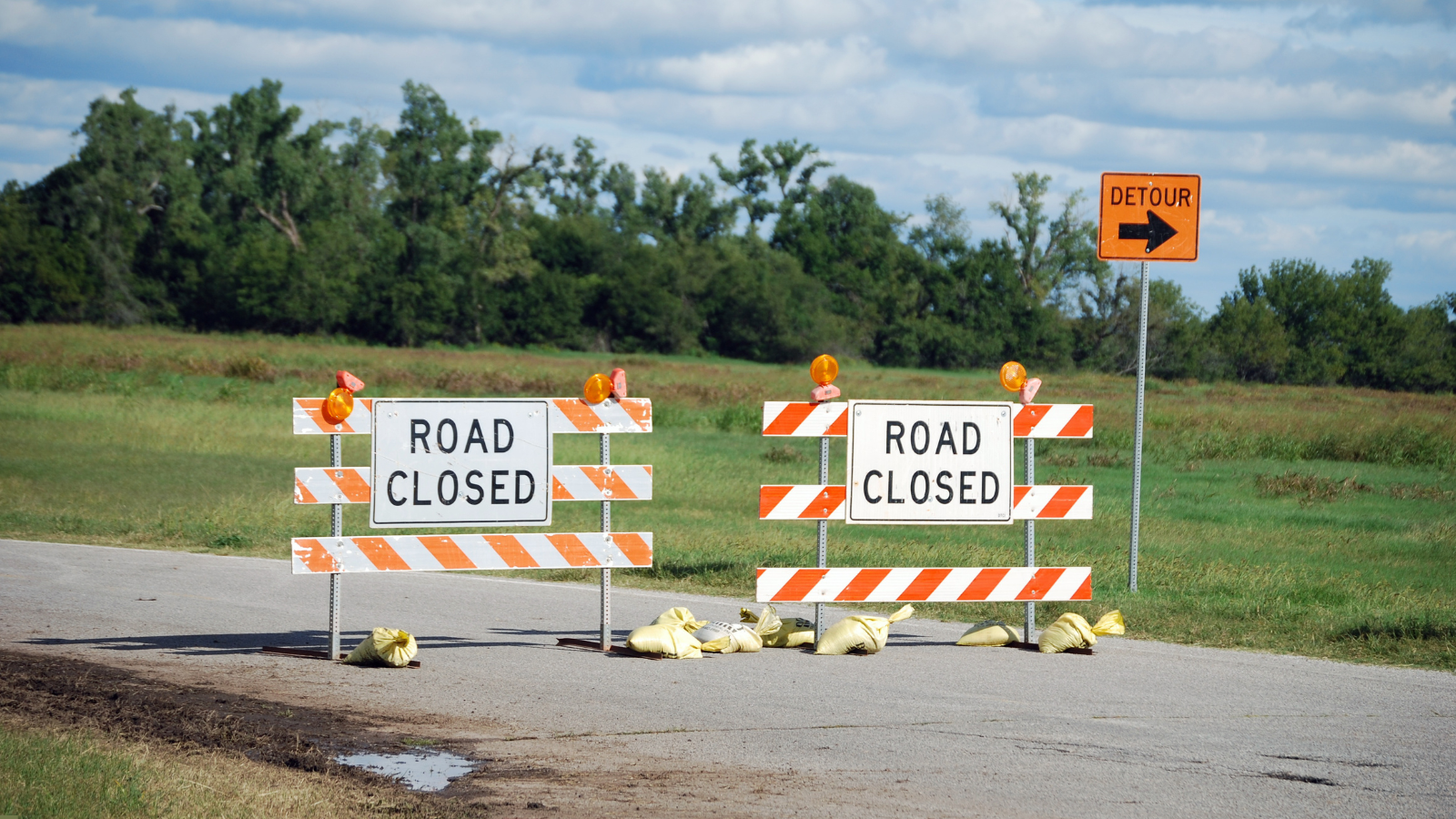two barricades stating road closed with a detour sign